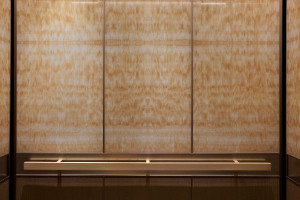 FSRT768 Интерьер лифта Levele-105 с верхними панелями из стекла медового оникса vivistone со стандартной отделкой; нижние панели из склеенной бронзы с естественной патиной и рисунком дождя; прямоугольный поручень из атласной бронзы в Intercontinental dall